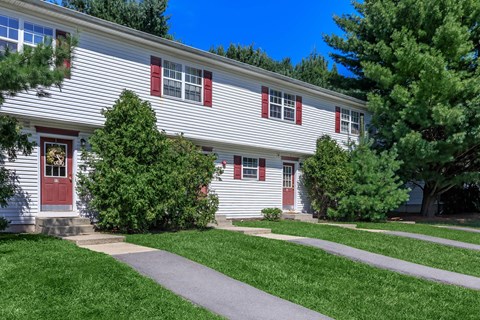 a white house with red shutters and a sidewalk