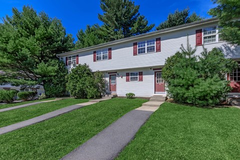a white house with red shutters and a walkway in front of a yard