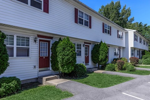 a white house with red doors and a lawn