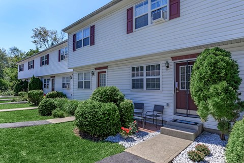 the front of a white house with a lawn and a patio