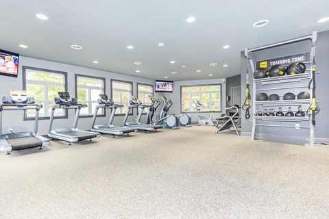 a gym with treadmills and weights in a room with windows