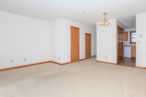 an empty living room with white walls and a wooden door