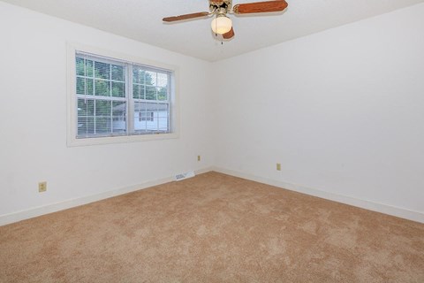 an empty living room with a ceiling fan and a window