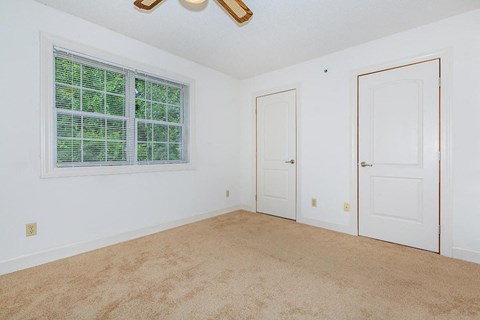 an empty bedroom with a window and a door