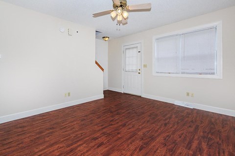 an empty living room with a ceiling fan and a window