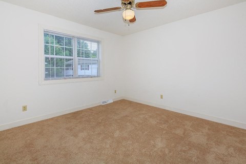 an empty living room with a ceiling fan and a window