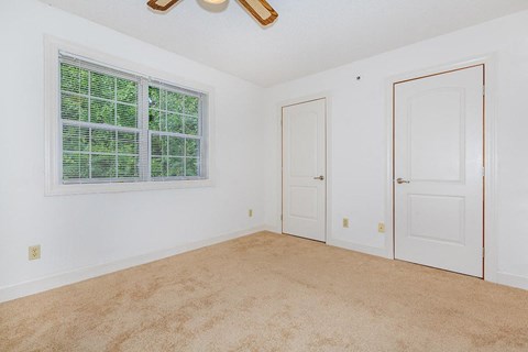 an empty bedroom with a window and a door