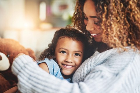 a woman hugging a little girl with a teddy bear