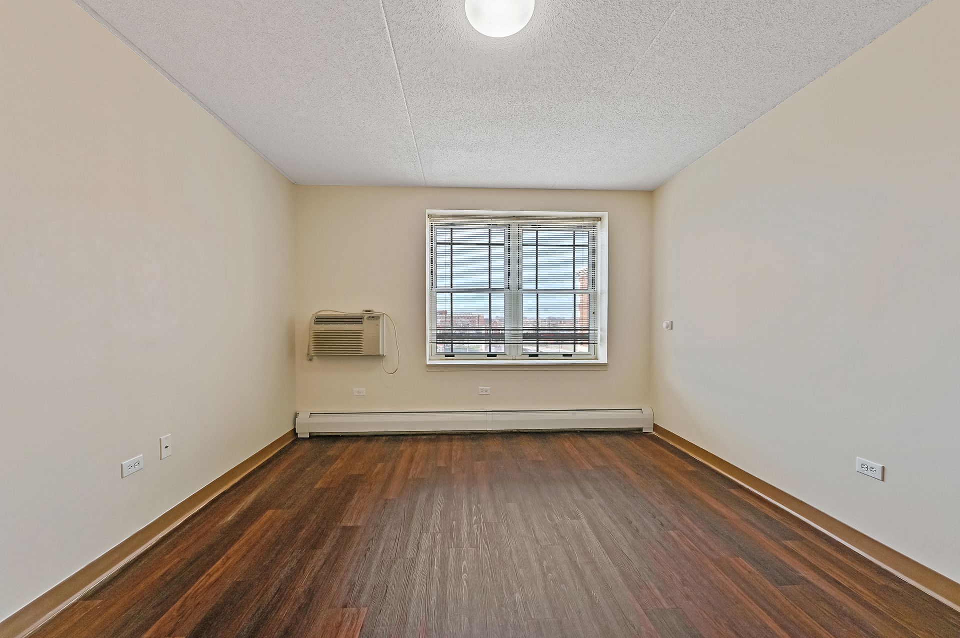 an empty living room with wood floors and a window