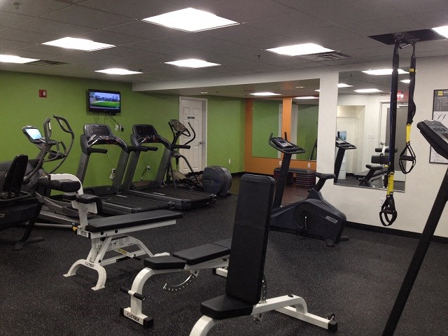 a gym with various exercise equipment and a tv
