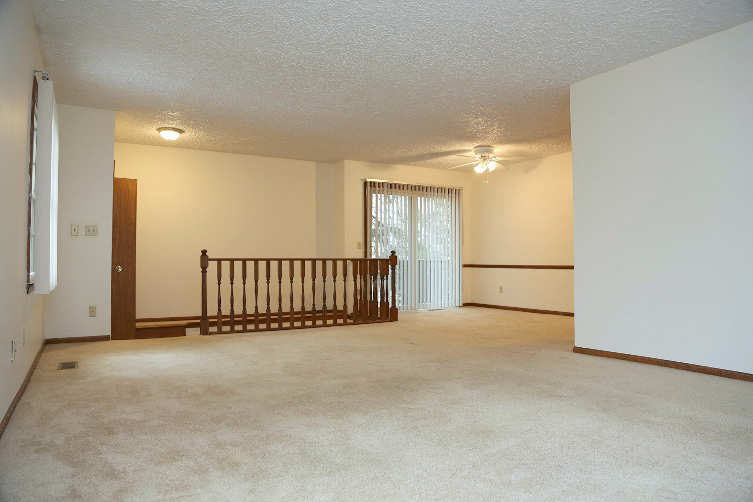 the spacious living room of an empty house with a railing in the corner