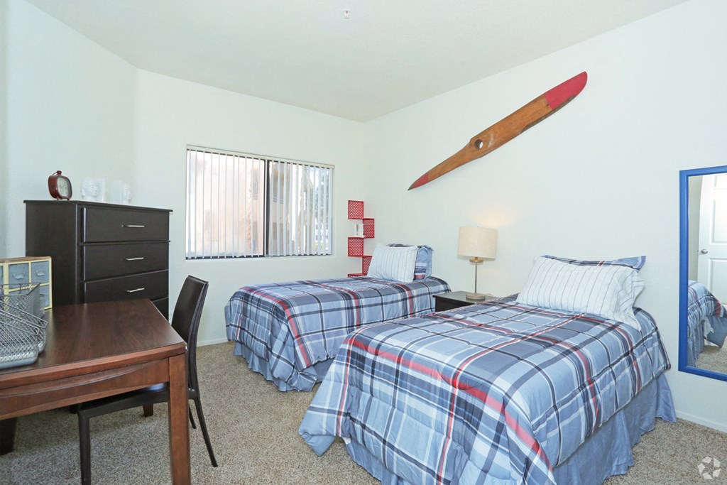 a bedroom with two beds and a desk with a surfboard on the wall