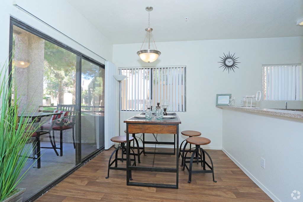 a dining room with a table and stools and a balcony