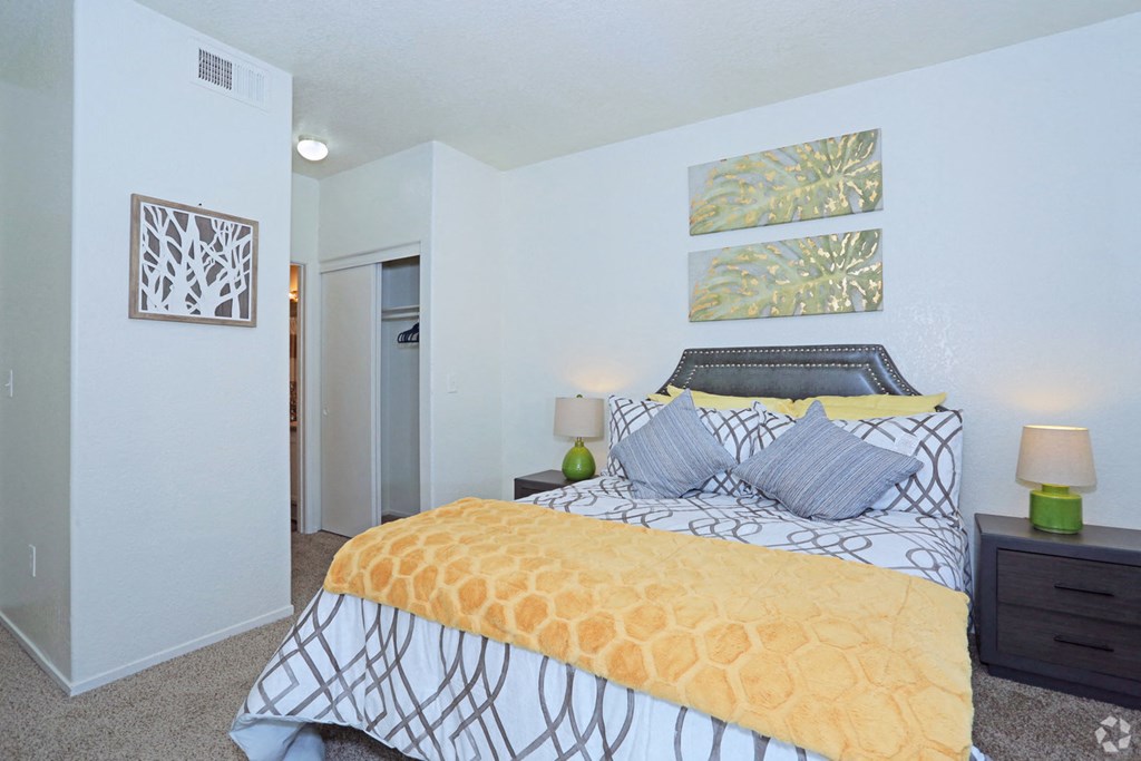 a spacious bedroom with a yellow bed and white walls
