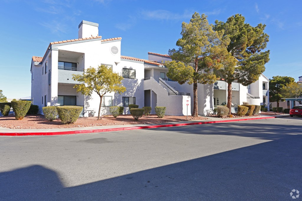 a white building with a street in front of it and trees