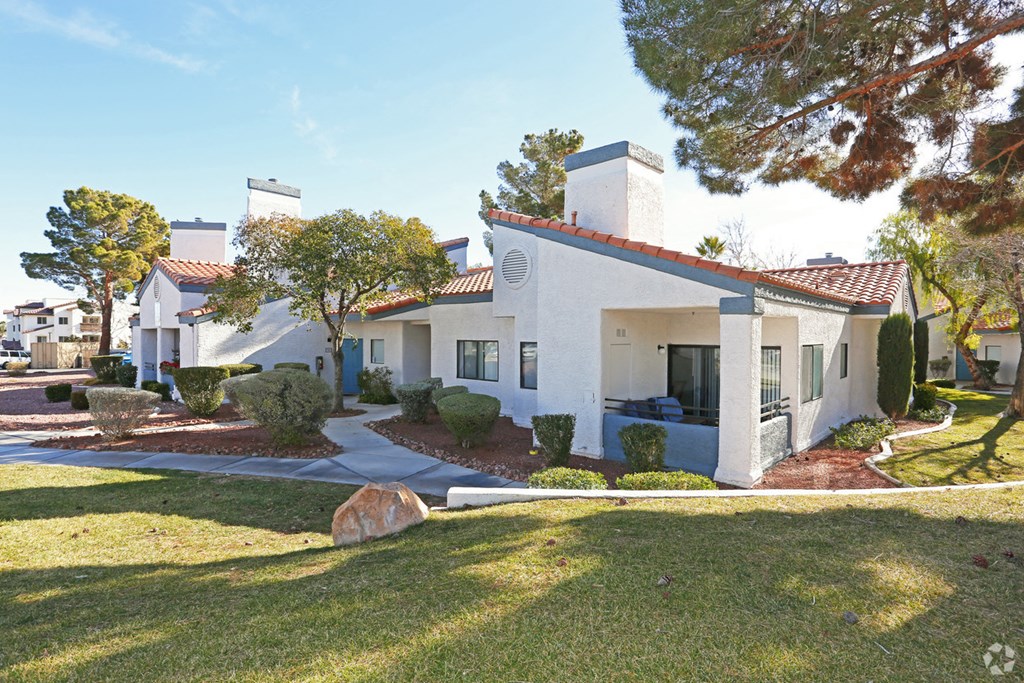a white house with a yard and trees and a sidewalk