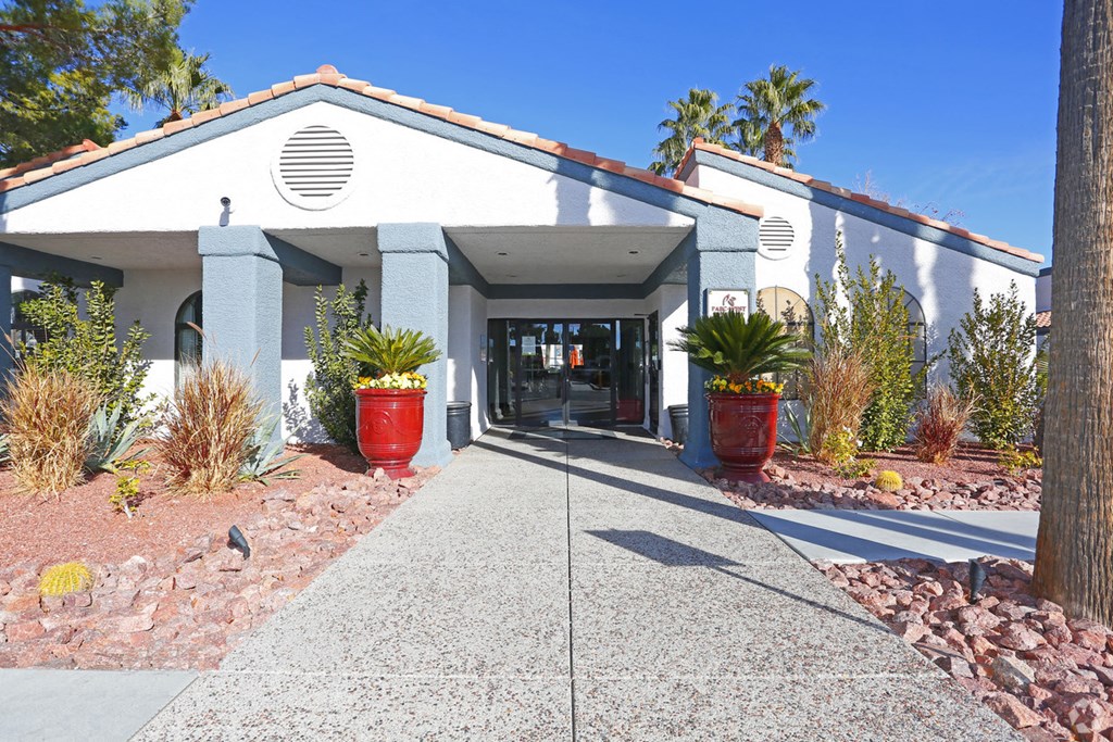the front of a building with a walkway and palm trees