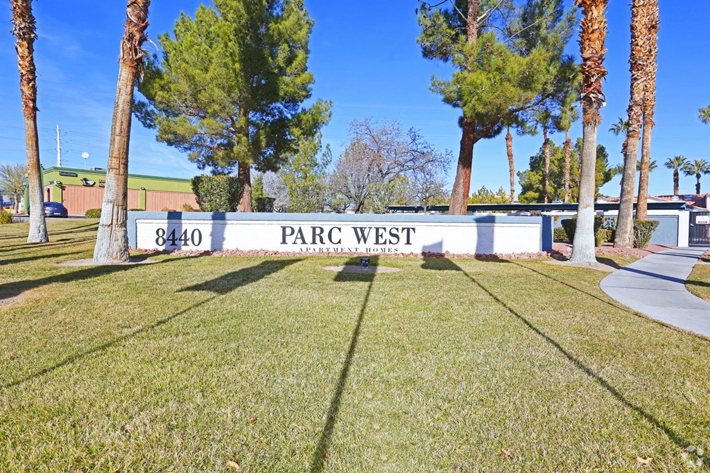 a sign that says park west in front of a lawn with palm trees