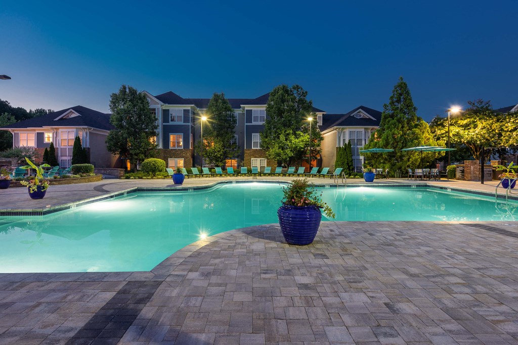 a swimming pool at night with apartments in the background