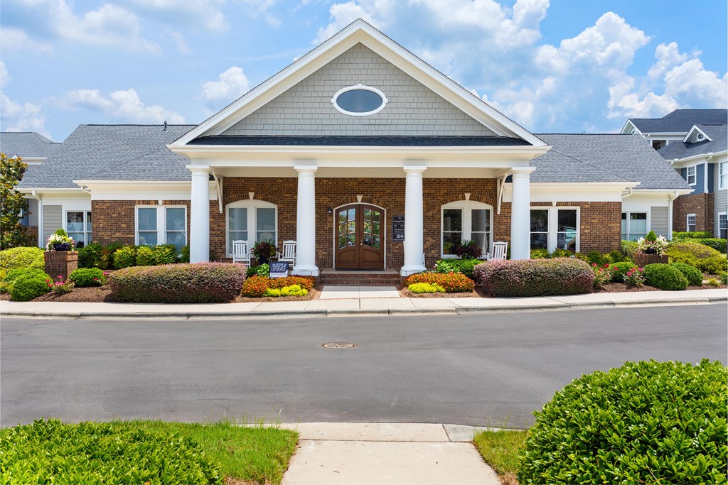 the front of a brick house with white pillars and a porch