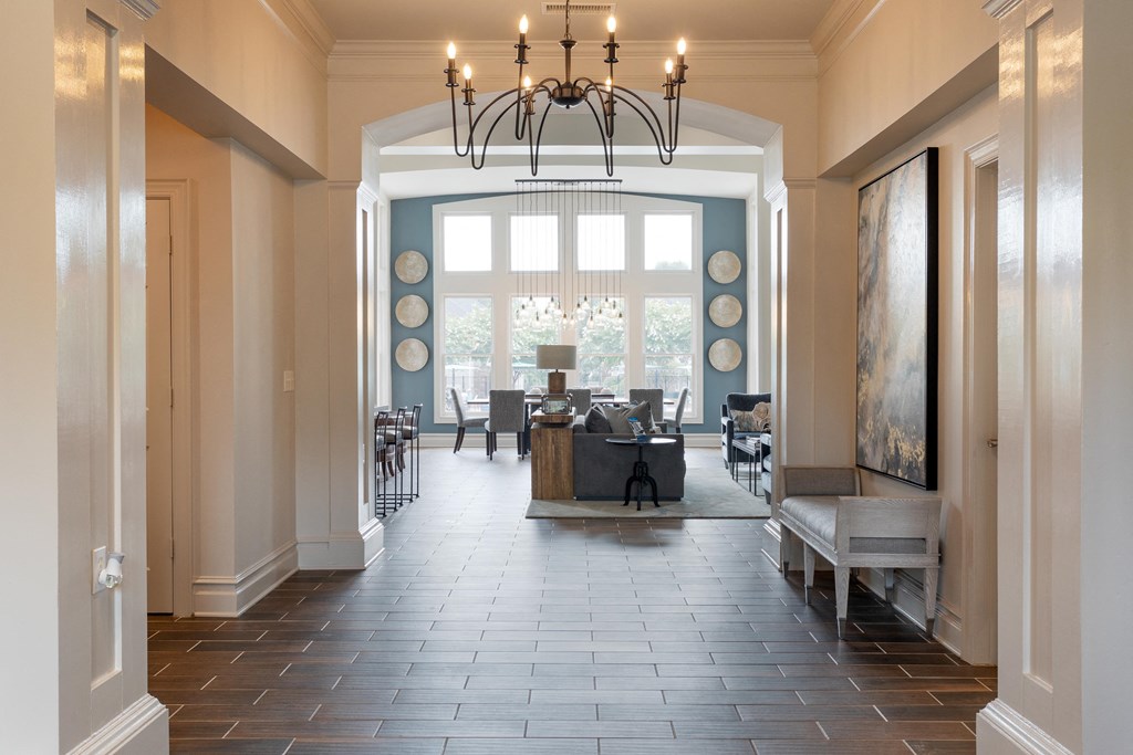 a large hallway with a chandelier and a table and chairs in the center