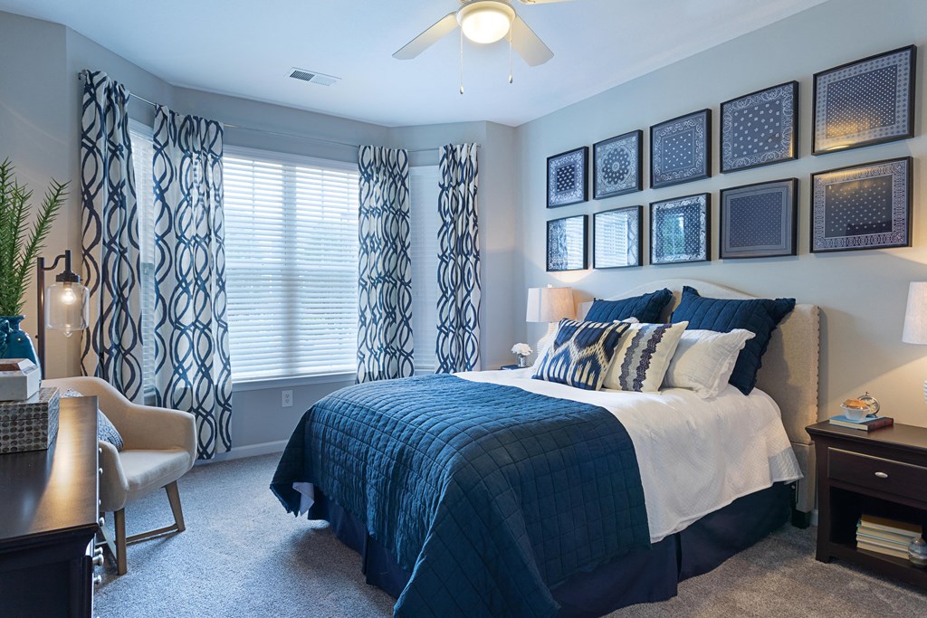 a bedroom with blue and white bedding and pictures on the wall