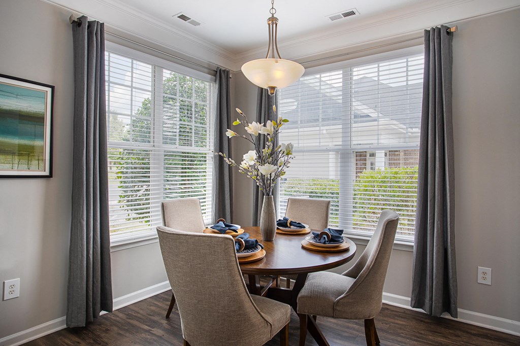 a dining room with a table and chairs and large windows
