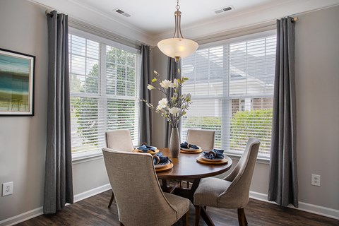 a dining room with a table and chairs and large windows