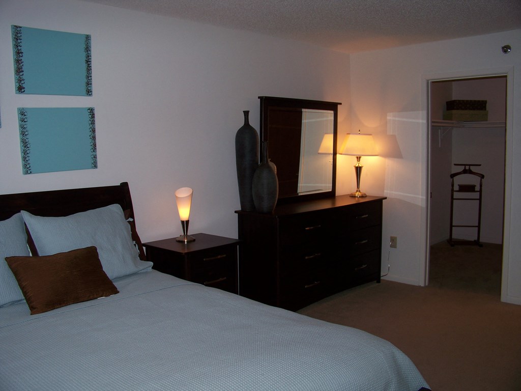 a bedroom with a bed and a dresser with a mirror