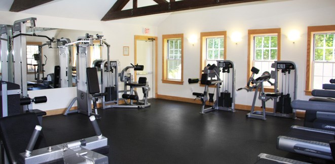 a gym with cardio equipment and weights on the floor