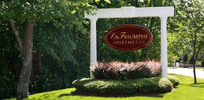 a sign apartments in front of some trees and bushes