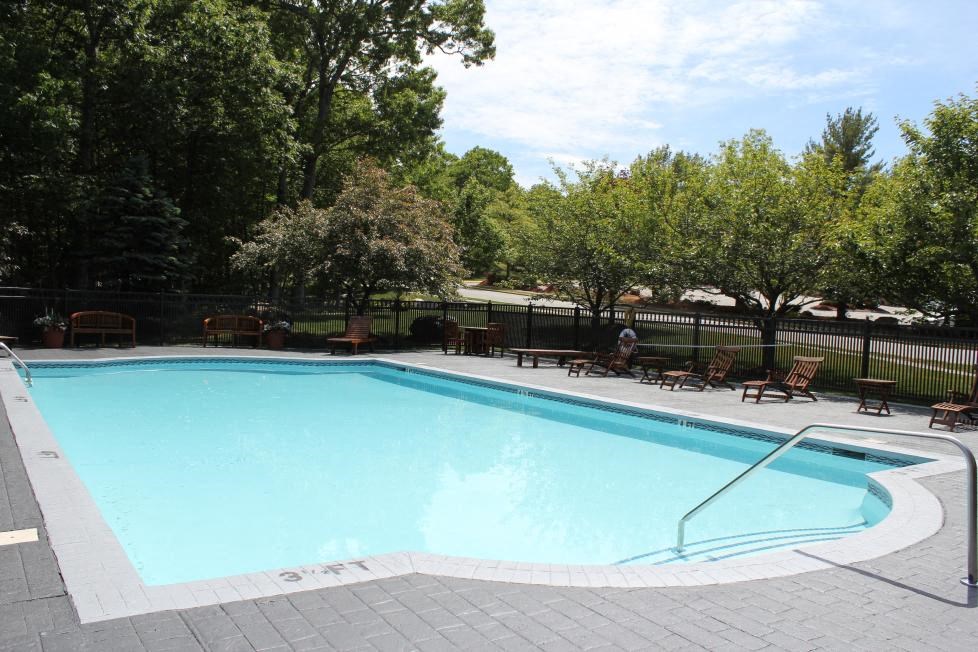 a swimming pool with chairs and a fence around it
