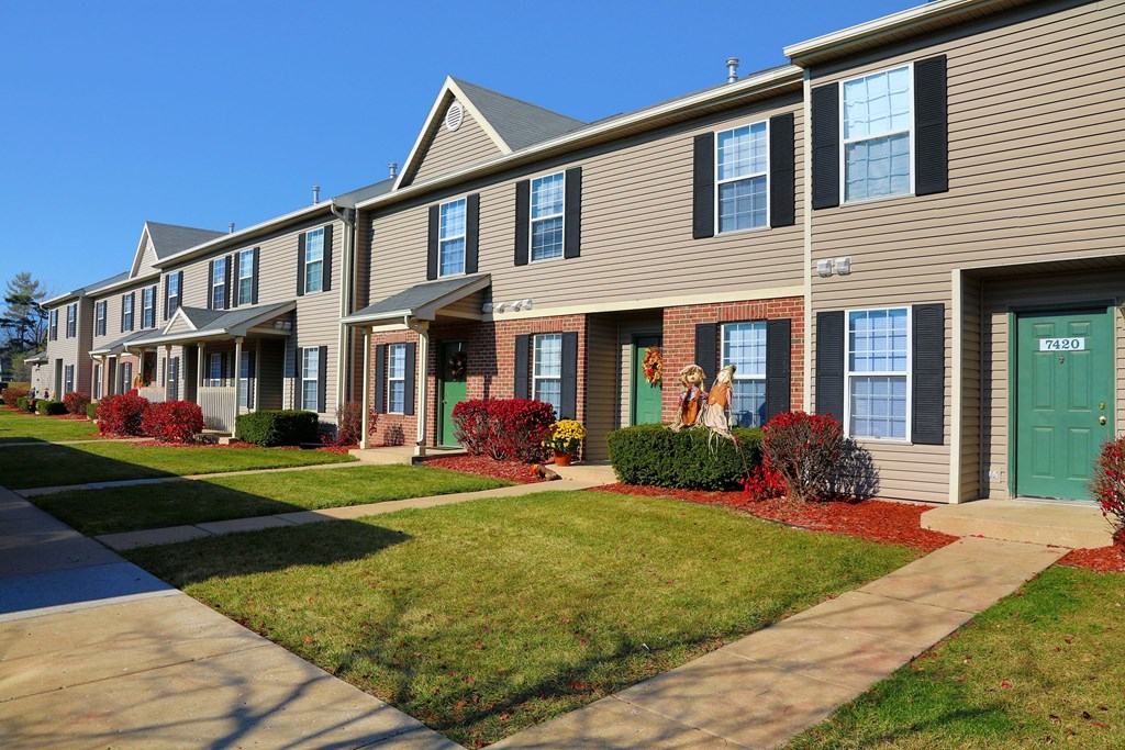 a row of town houses with green doors on a sidewalk