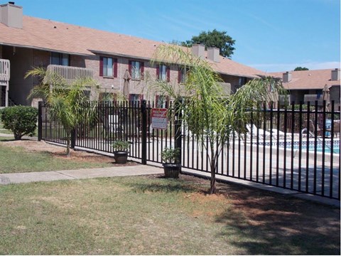 a house with a swimming pool behind a wrought iron fence