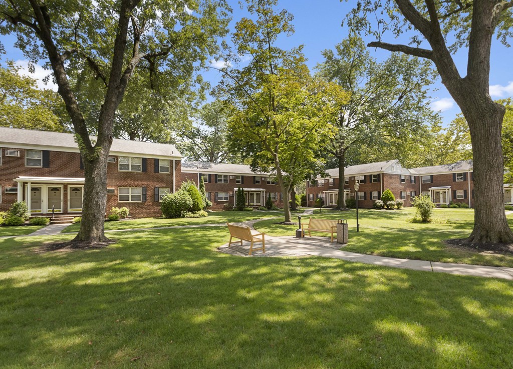 a courtyard with benches and trees in front of a brick building