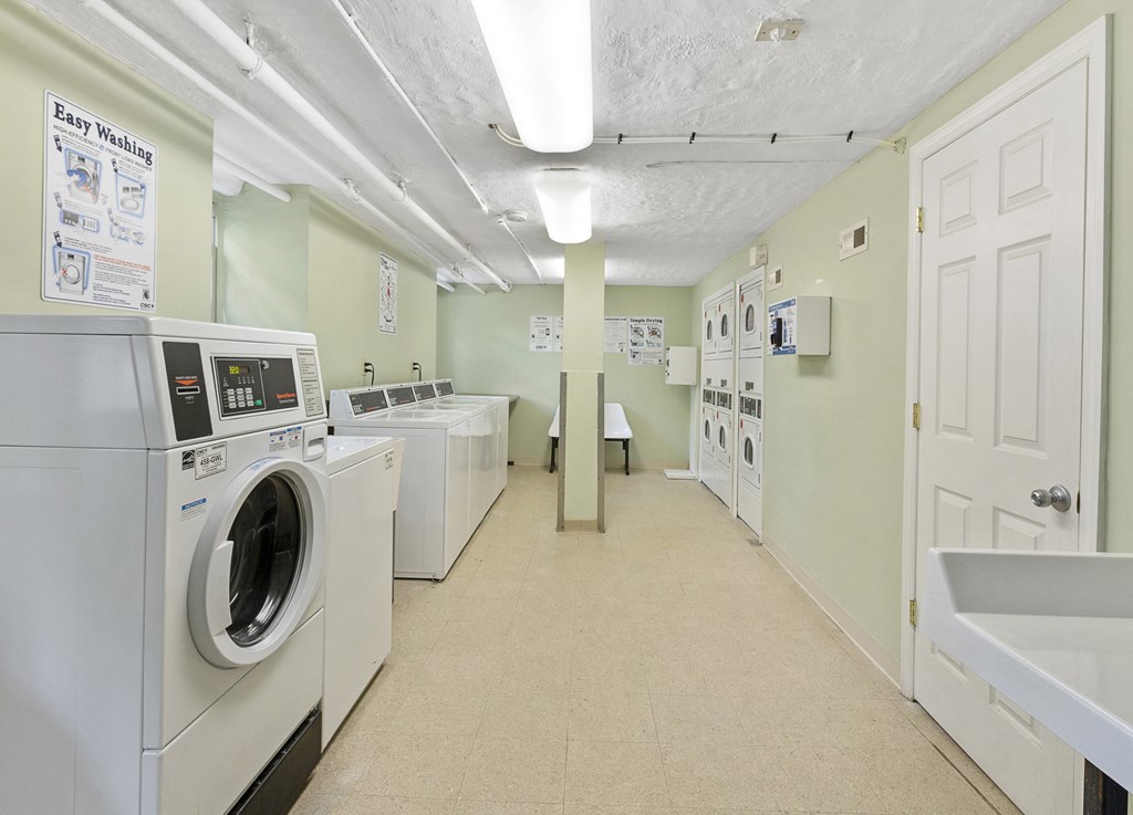a laundry room with washers and dryers and a row of washing machines