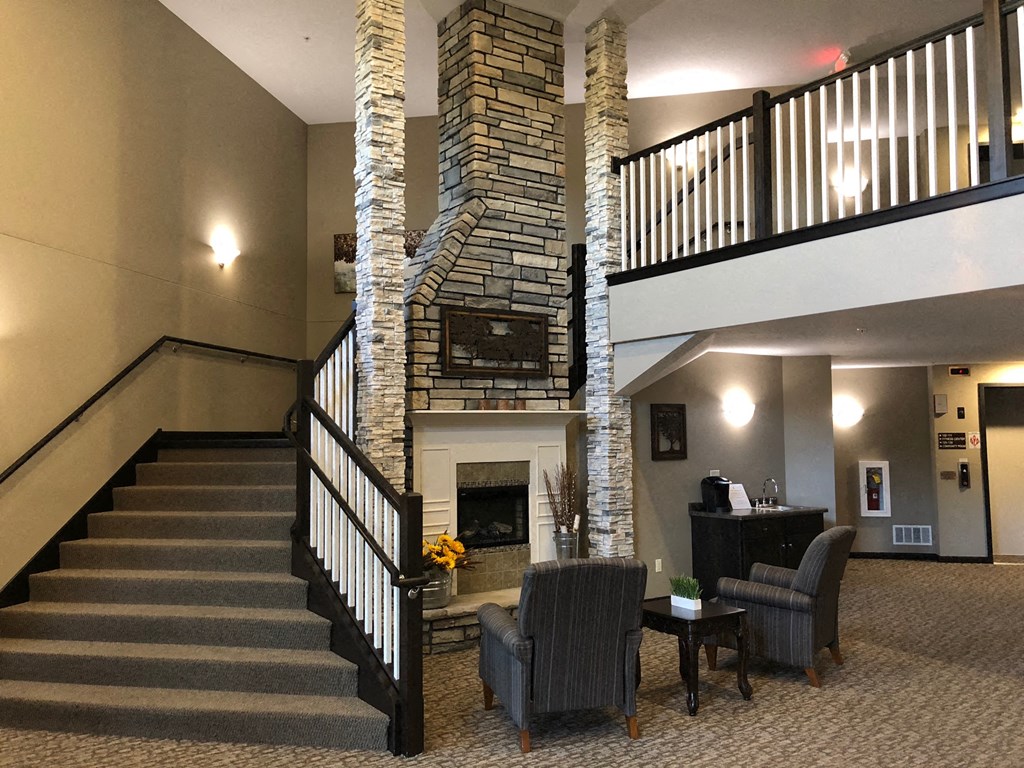 a lobby of a hotel with a fireplace and stairs