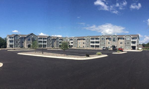 an exterior view of an apartment building in a parking lot