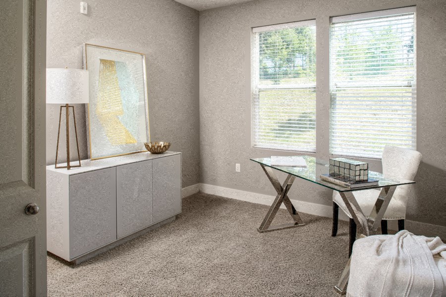 a home office with a glass desk and a large window