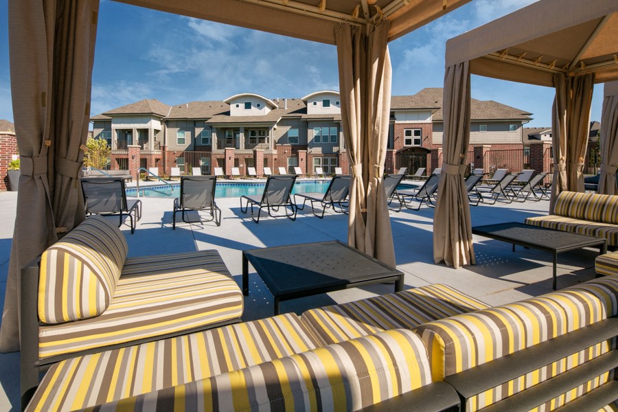 a pool with lounge chairs and tables in front of a building