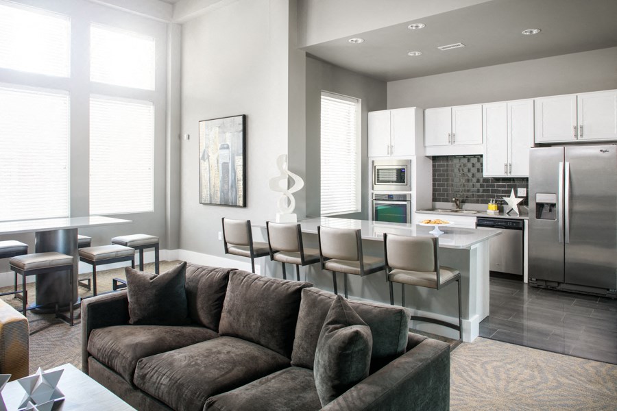 a living room with a couch and chairs in front of a kitchen
