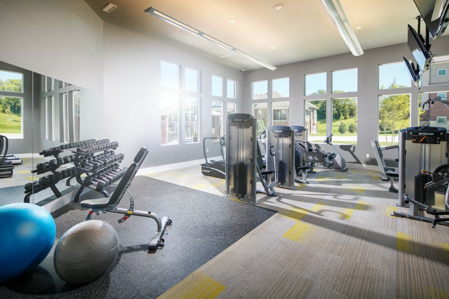 a gym with cardio equipment and windows in a building