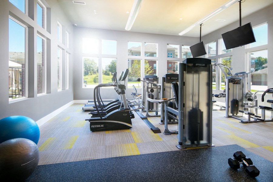 a gym with cardio equipment and windows in a building