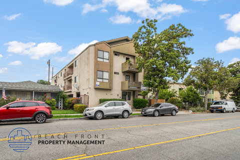 A row of apartment buildings with cars parked in front.