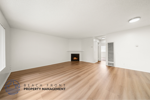 A spacious room with a fireplace and wooden flooring.