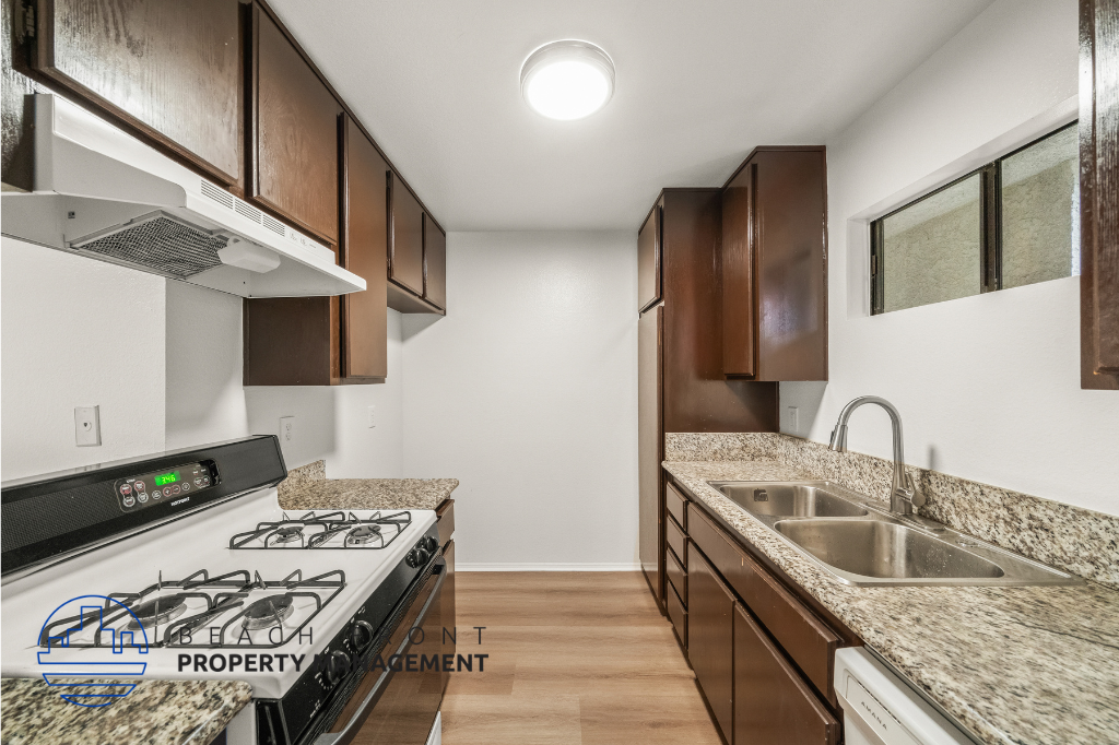 A kitchen with a black stove top oven and brown cabinets.