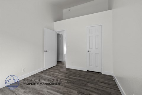 the living room of an apartment with white walls and wood flooring