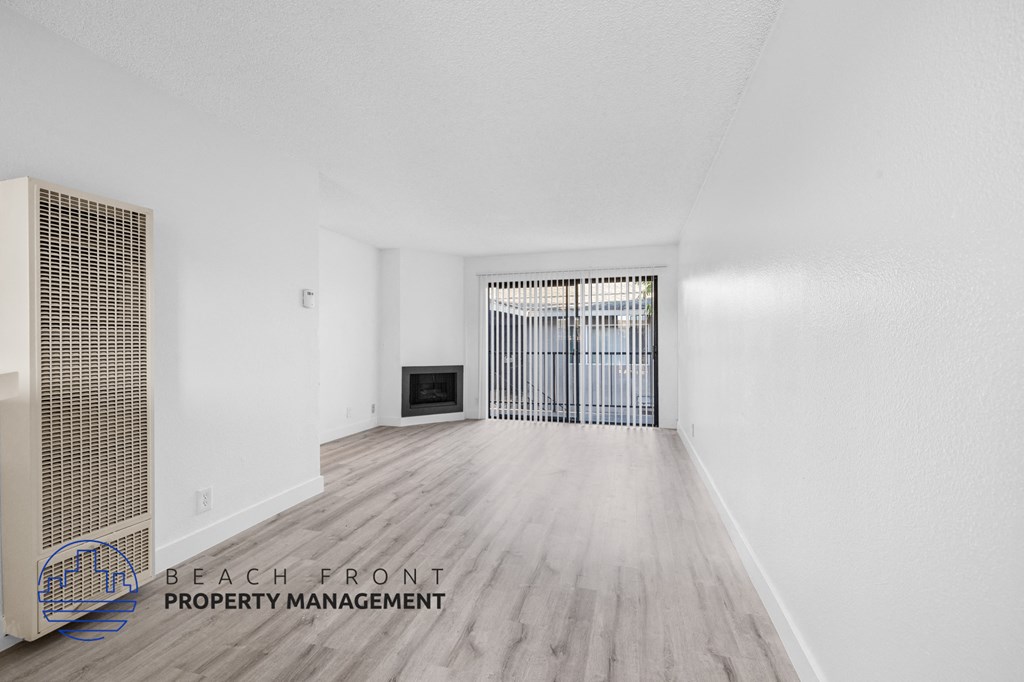 a living room with white walls and wood flooring and a fireplace