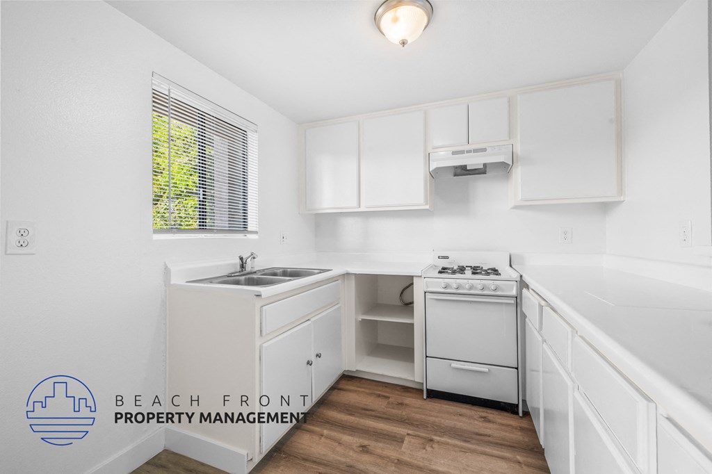 a white kitchen with white cabinets and white appliances and a window