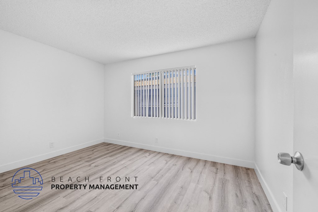 the spacious living room of this manufactured home has hardwood flooring and white walls